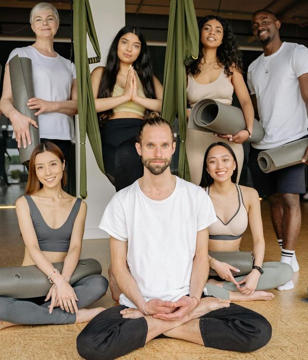 Diverse group of people smiling and preparing for a yoga class.